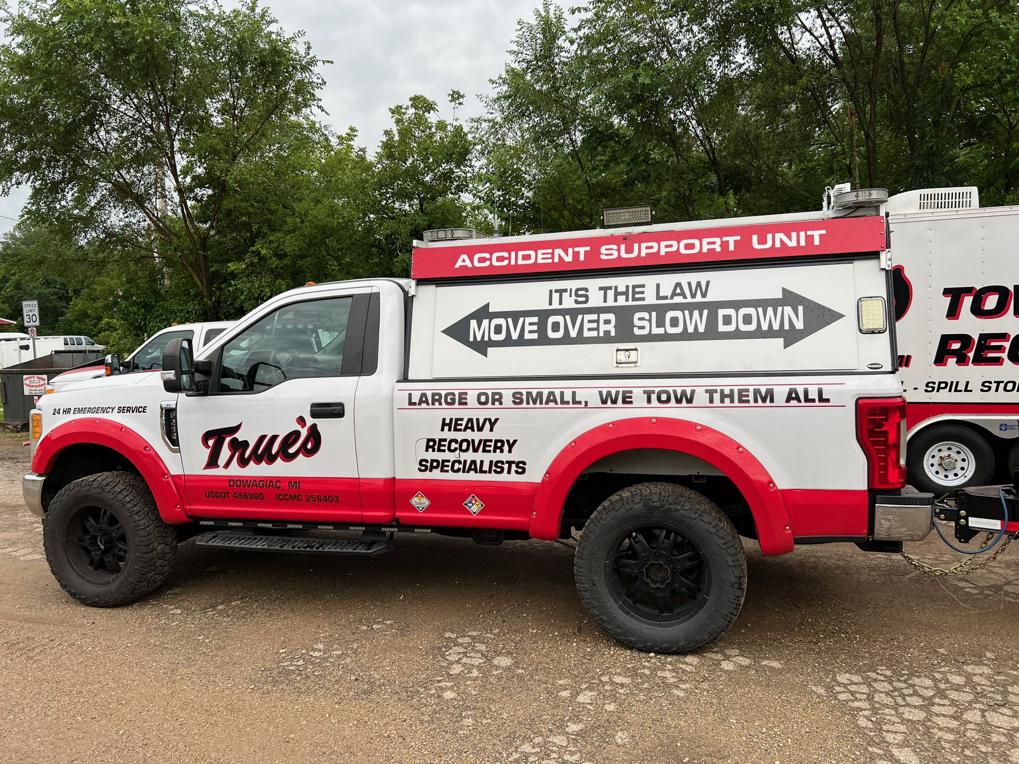 A custom black towing dolly parked in front of two fifty three foot trailers.
